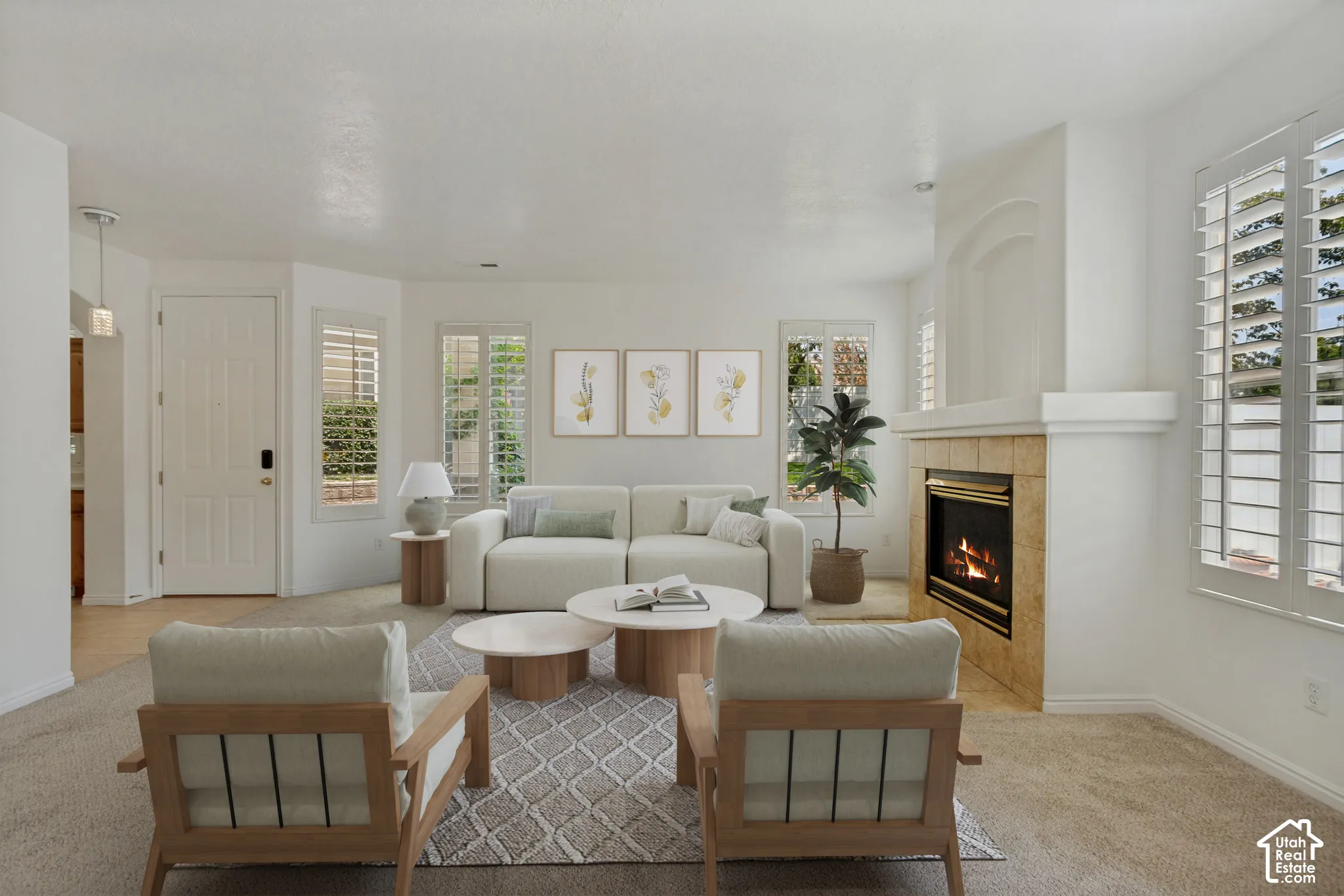 Light-filled living area featuring a built-in fireplace with stone-finish surround, multiple windows with plantation shutters, and light-toned carpet flooring