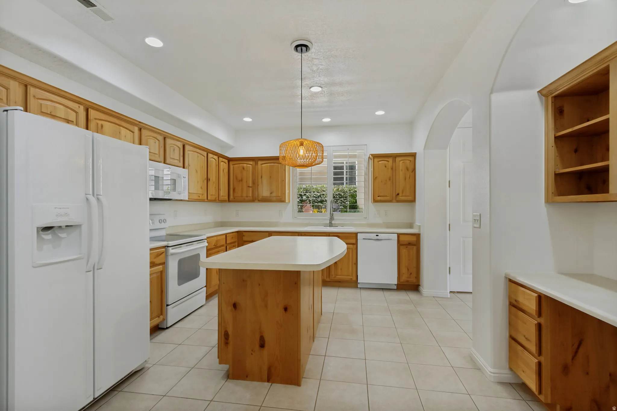 Kitchen featuring wood cabinetry, a center island with countertop, tile flooring, and a window above the sink