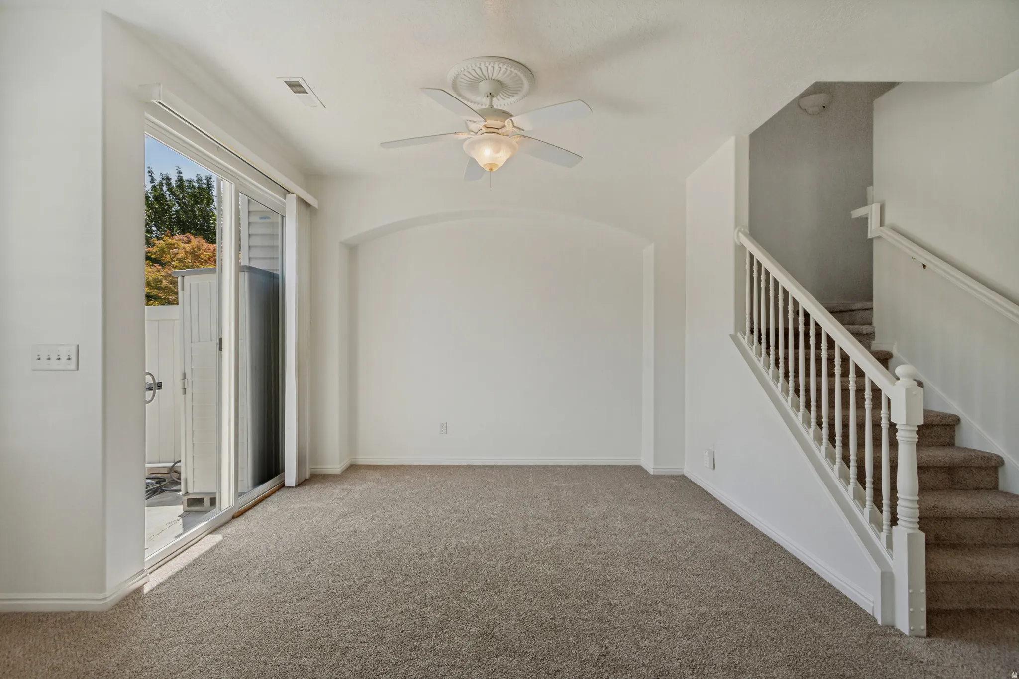 Neutral carpet flooring, white walls, and a ceiling fan with integrated lighting