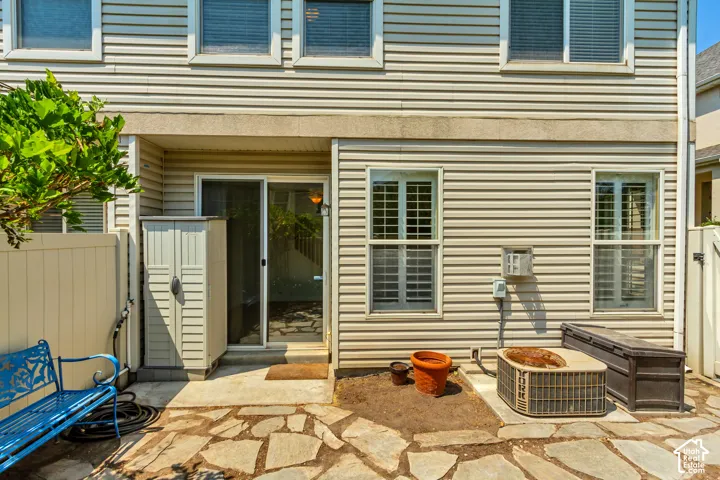 Flagstone patio with a sliding glass door entry, vinyl siding exterior, and privacy fencing