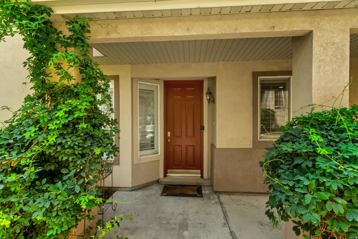 Covered entryway featuring a paneled door, exterior wall lantern, and concrete pathway