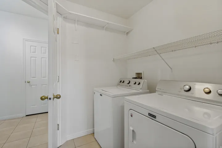 Laundry area featuring a top-load washing machine, front-load dryer, and wire shelving
