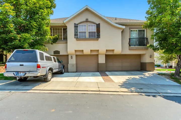 Stucco exterior with decorative shutters, two-car garage, and a Juliet balcony with wrought iron railing