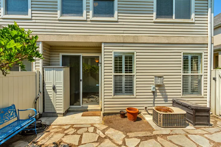 Flagstone patio with a sliding glass door entry, vinyl siding exterior, and privacy fencing