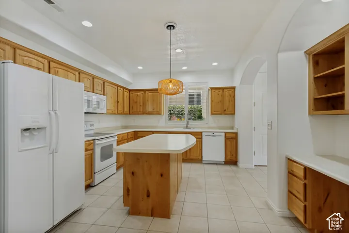 Kitchen featuring wood cabinetry, a center island with countertop, tile flooring, and a window above the sink