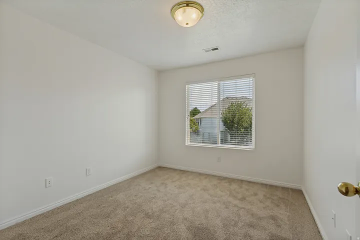 Neutral-toned carpeting, white painted walls, and a window with blinds