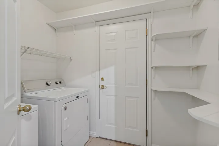 Utility area with white shelving units, wire rack storage, and a paneled door