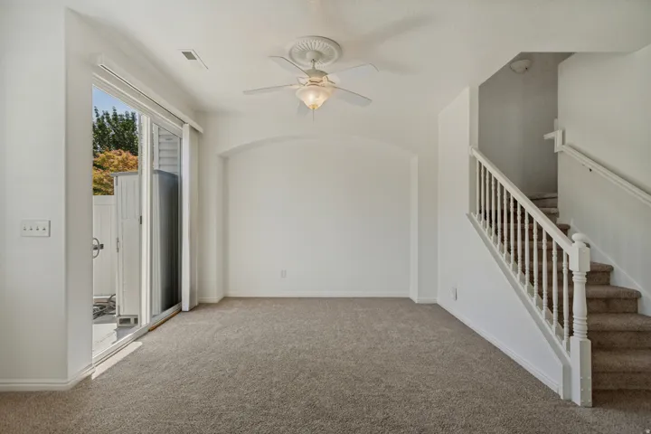Neutral carpet flooring, white walls, and a ceiling fan with integrated lighting