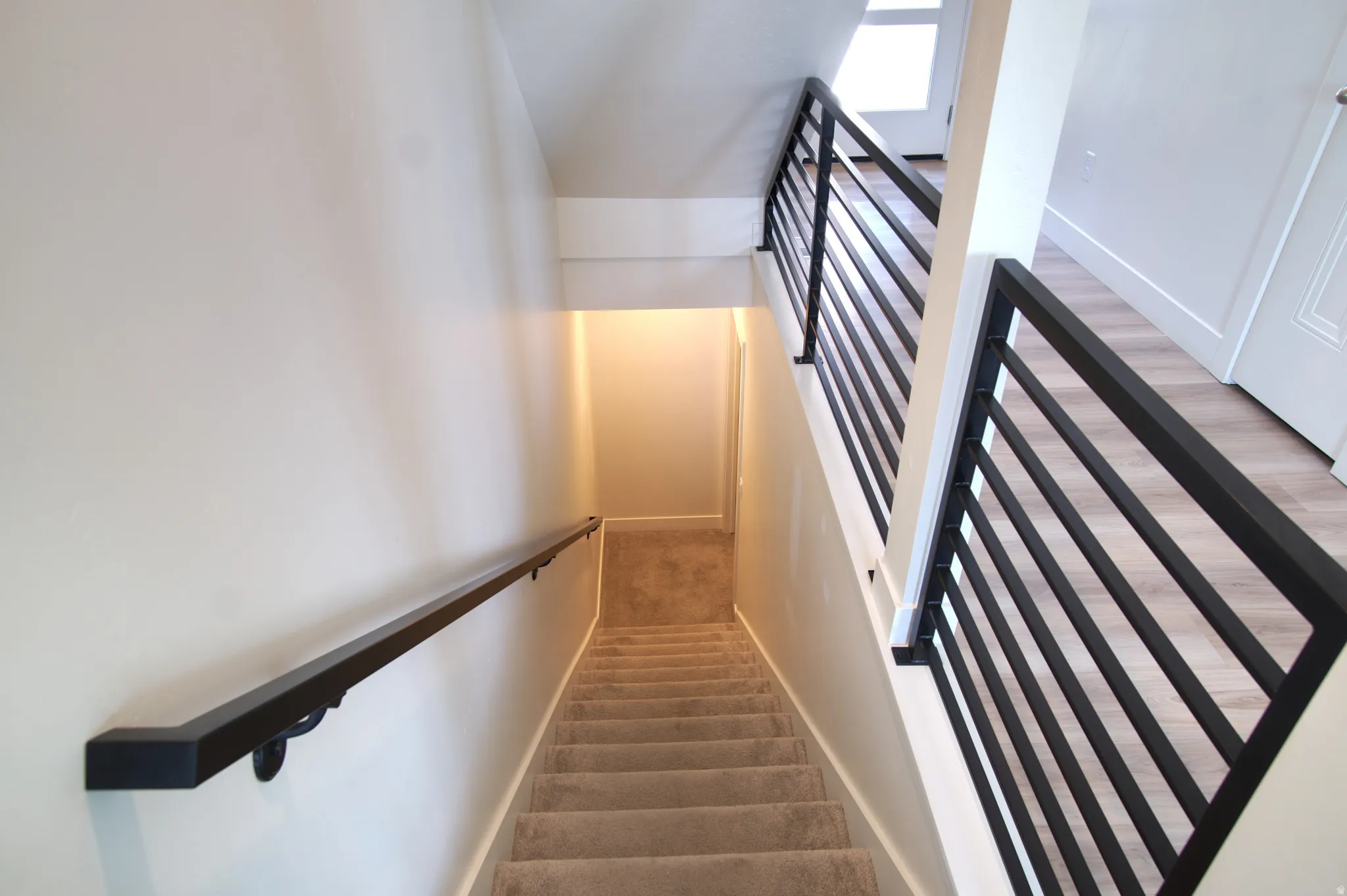 Staircase with carpeted treads and a black metal handrail