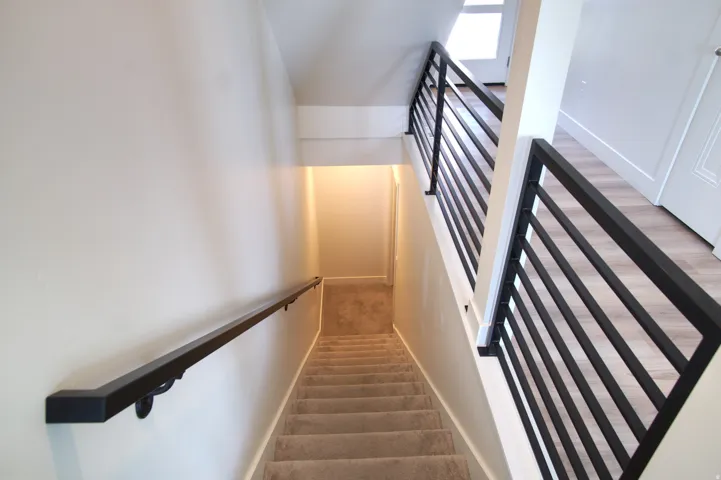 Staircase with carpeted treads and a black metal handrail