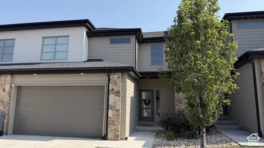 Two-story townhome with stone accents, horizontal siding, and a two-car garage