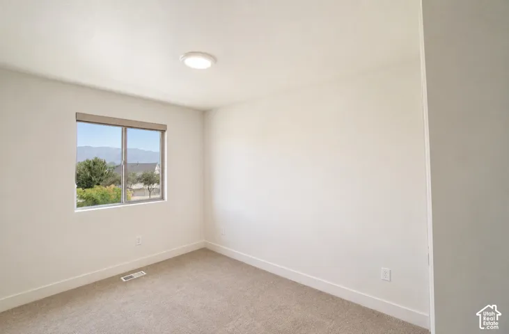 Neutral wall paint, window with roller shade, carpeted flooring, and a flush mount ceiling light