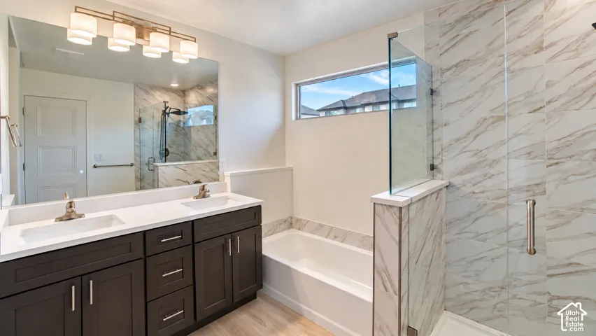 Dual-sink vanity with a solid-surface countertop, floor-to-ceiling tiled shower with a glass enclosure, separate soaking tub, and large wall-mounted mirror with multi-bulb light fixture