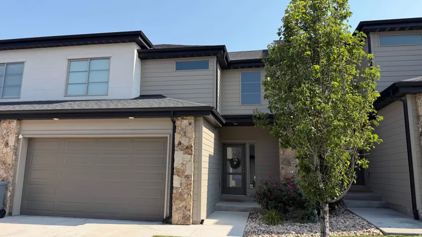 Two-story townhome with stone accents, horizontal siding, and a two-car garage