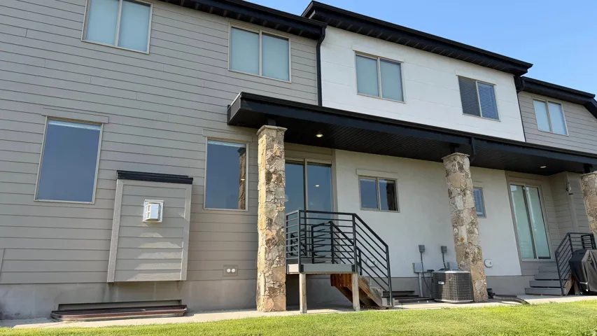 Multi-level exterior featuring horizontal siding, white stucco, stone-clad columns, and multiple windows