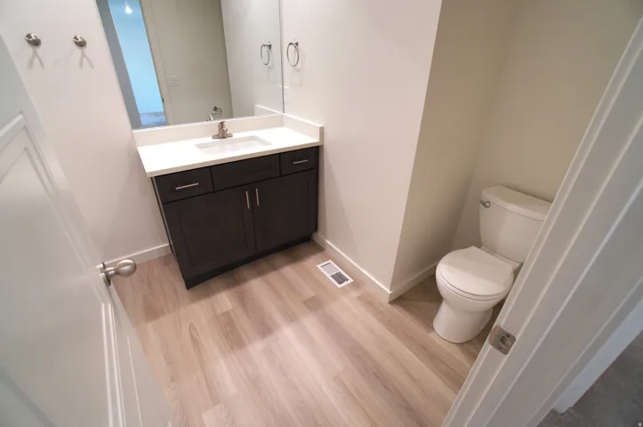 Modern vanity with a white countertop and dark wood-finish cabinetry, under-mount sink, brushed nickel faucet, and coordinating wall mirror