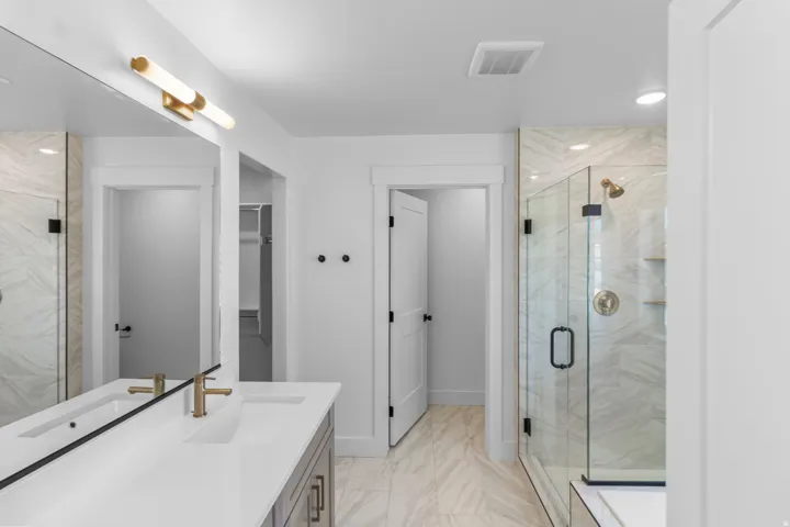 Dual vanity with undermount sinks, gold-finish fixtures, and a large mirror