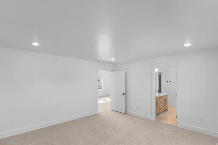Recessed lighting illuminates the room, featuring light-colored carpeting