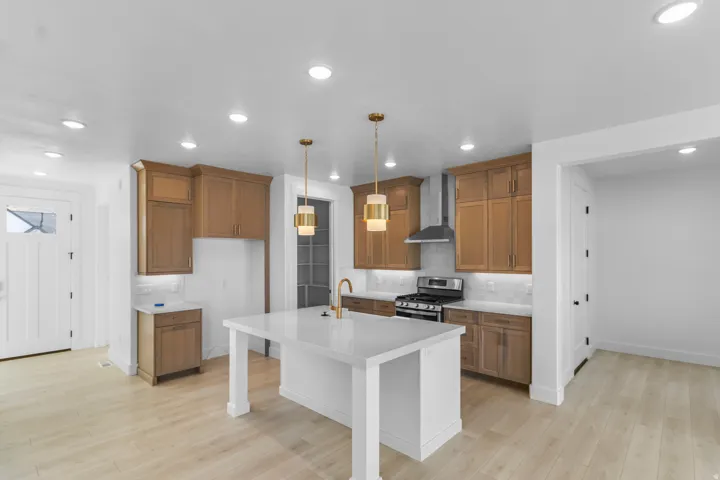 Kitchen featuring wood-finish cabinetry, stainless steel appliances, a white island with a quartz-finish countertop, and recessed lighting