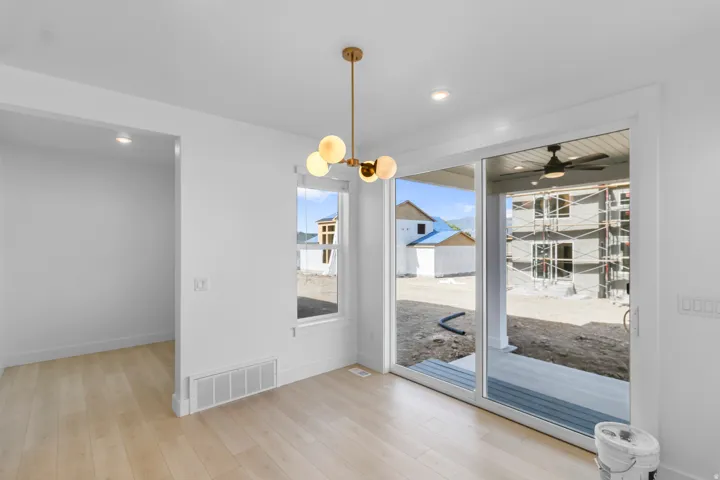 Light wood-finish flooring, recessed lighting, modern chandelier, large window, and sliding glass doors