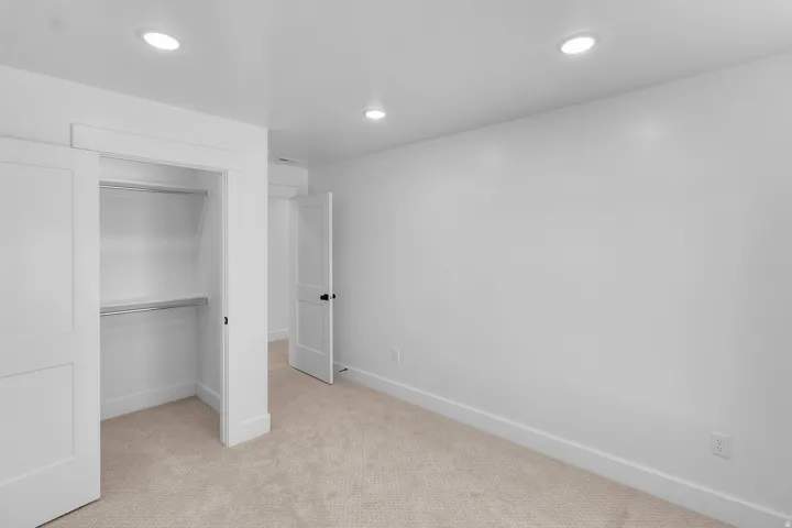 Recessed ceiling lighting, carpet flooring, flat panel interior doors, and a built-in closet with shelving and hanging rods