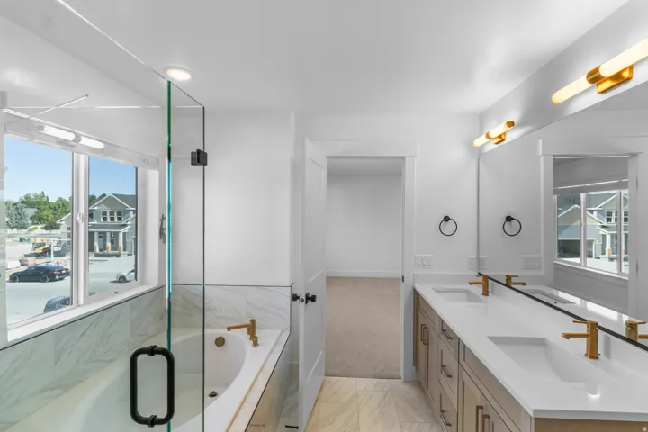 Dual vanity with white countertops, undermount sinks, and gold-finish fixtures
