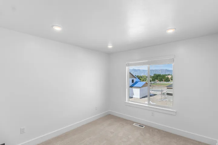 Recessed ceiling lighting, neutral wall finishes, carpeted flooring, and a large window with mountain scenery