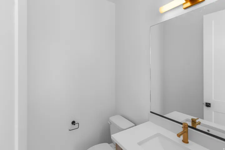 Vanity with an integrated sink, polished gold-tone faucet, and a large mirror with a black frame