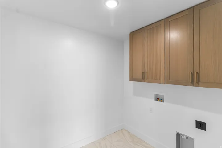 Recessed lighting illuminates wood-finish cabinetry with linear hardware, complemented by light-toned tile flooring