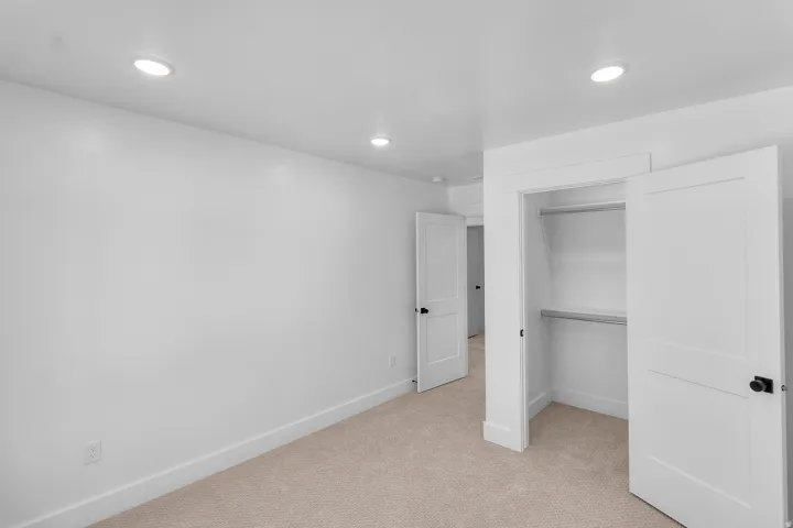 Recessed ceiling lighting, white interior doors, closet with shelf and hanging rod, and neutral-toned carpet flooring