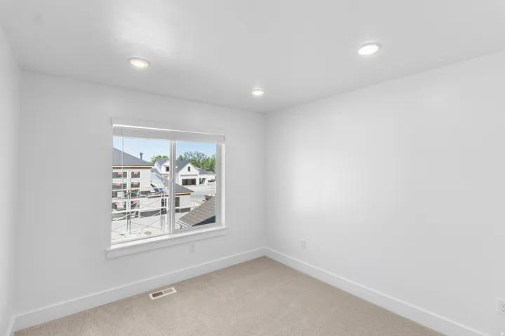 Recessed ceiling lighting, white walls, carpet flooring, window with blinds, and white trim