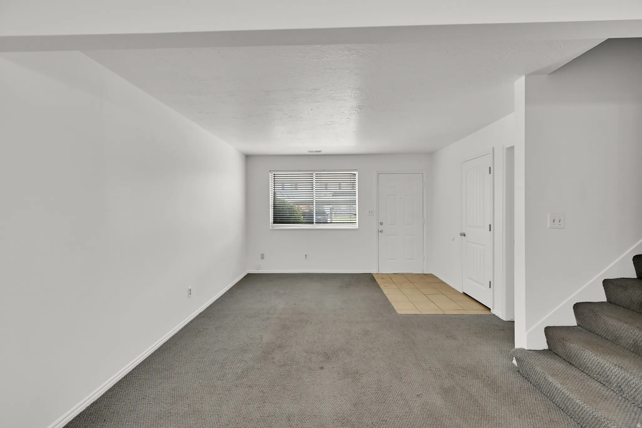 Neutral-toned carpeting, white interior walls, and a multi-pane window with blinds