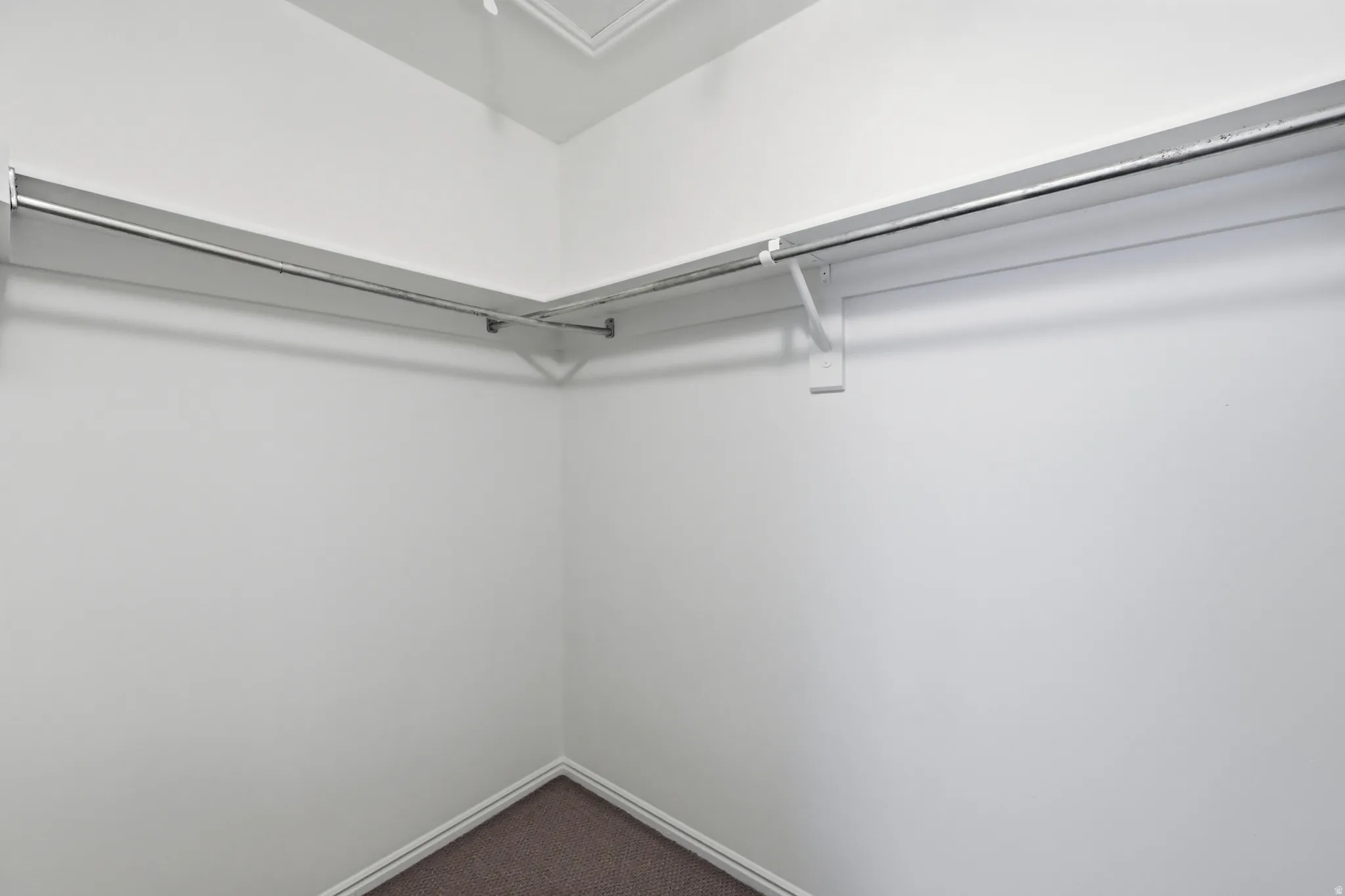 Corner closet with white walls and integrated metal hanging rods