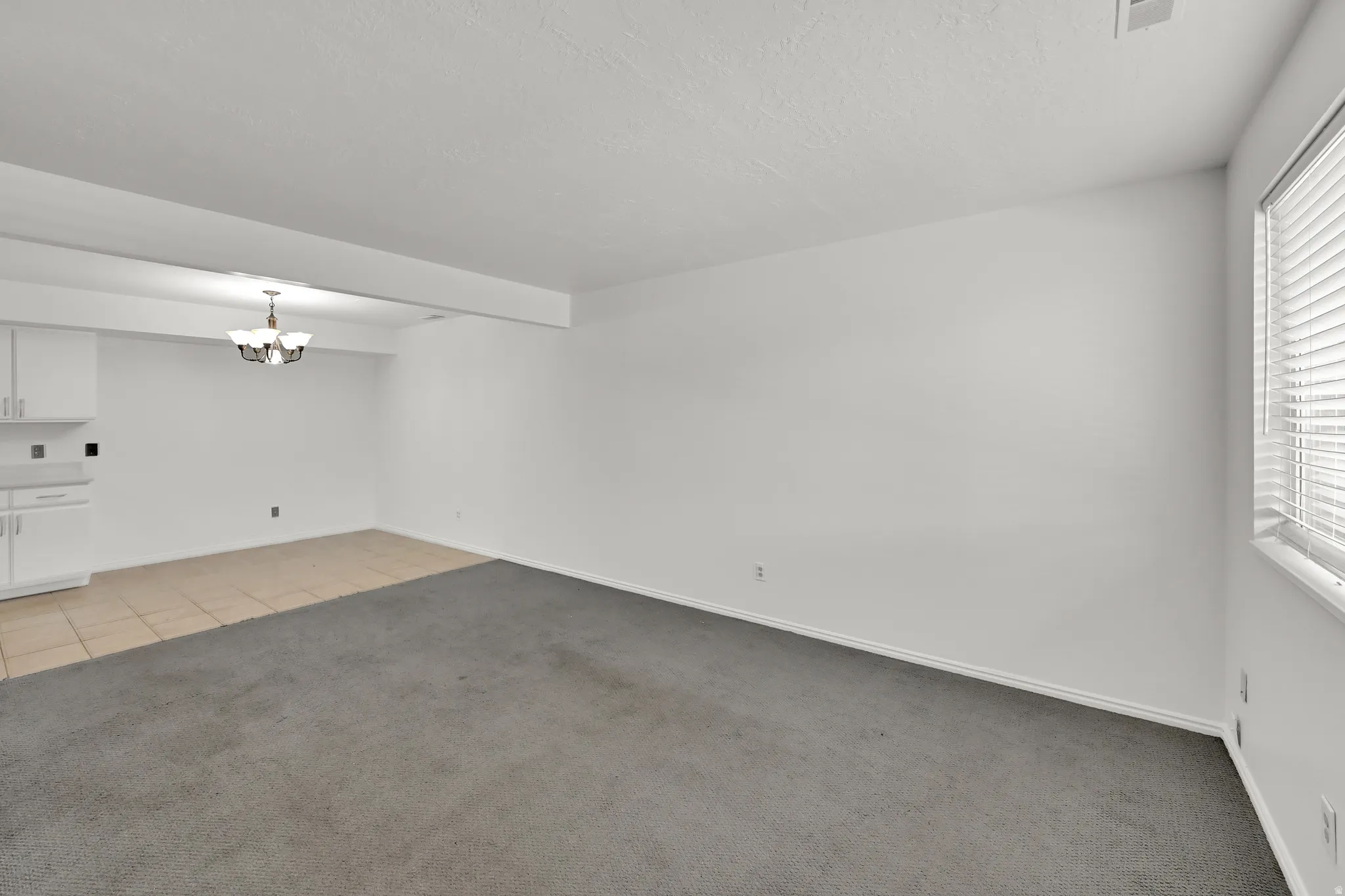 Recessed lighting, tile flooring, carpeted area, built-in cabinetry, and a multi-pane window with blinds