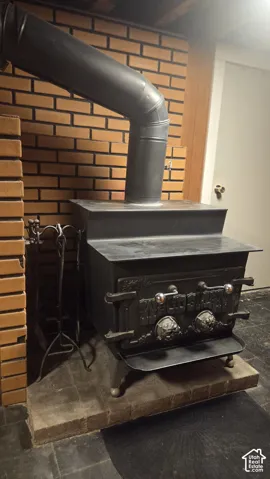 Cast iron wood-burning stove with ornate detailing, set against a brick wall