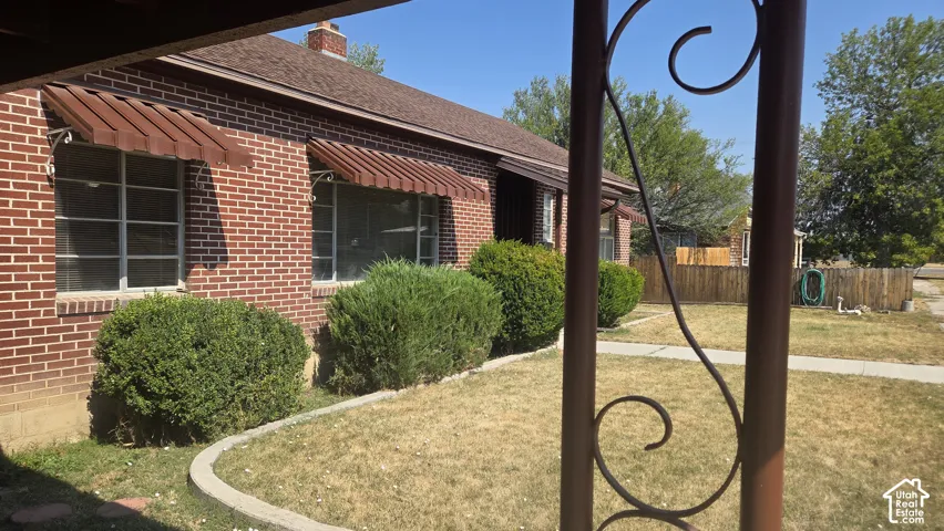 Brick exterior with awning-covered windows, a gabled roof, and a mature shrub landscape