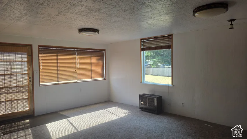 Carpeted room with multiple windows, and a permanent wall-mounted heating unit