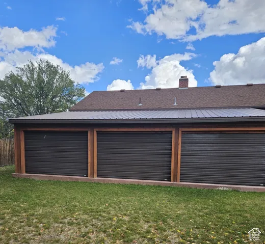 Three roll-up doors open to an outdoor rec room, featuring a metal roof and rain gutters