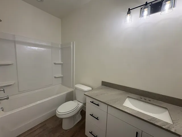 White vanity with dark hardware, integrated sink, and stone-finish countertop