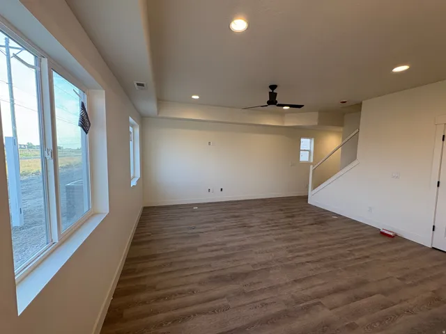 Recessed lighting, wood-finish flooring, ceiling fan, multiple windows, and a staircase with a glass panel