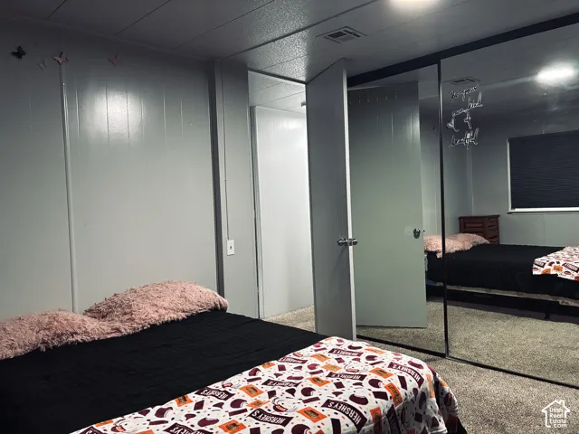 Wall paneling, ceiling paneling, carpet flooring, sliding mirrored closet doors, and recessed lighting