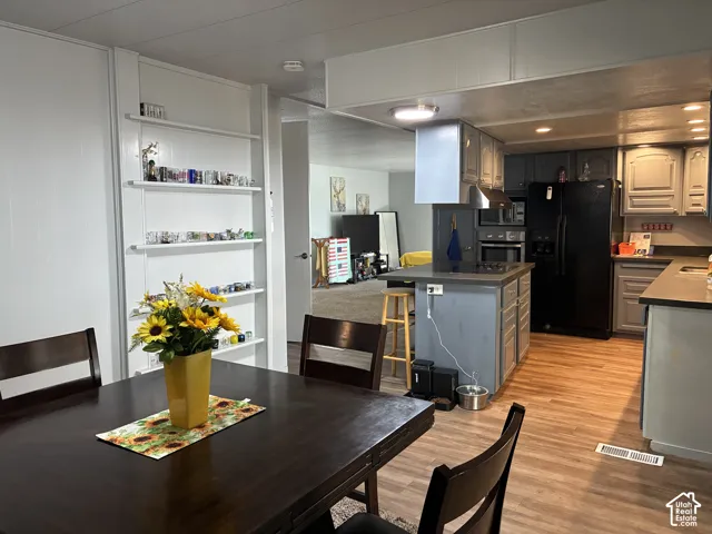 Kitchen featuring wood-finish flooring, an island with countertop, and black appliances