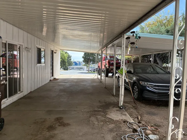 Carport with corrugated metal roofing, white vinyl siding, and concrete flooring