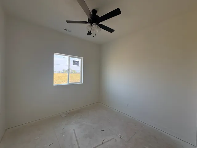 Bright interior space with a ceiling fan, a window, and neutral wall tones