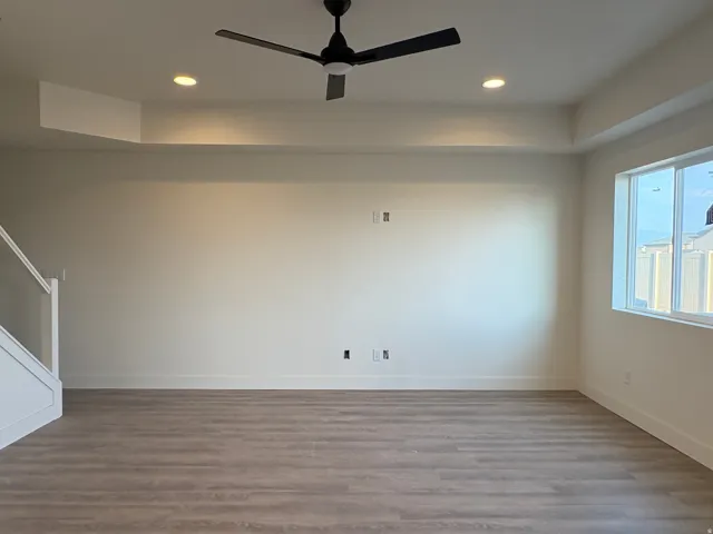 Spacious room featuring wood-finish flooring, recessed lighting, and a contemporary ceiling fan