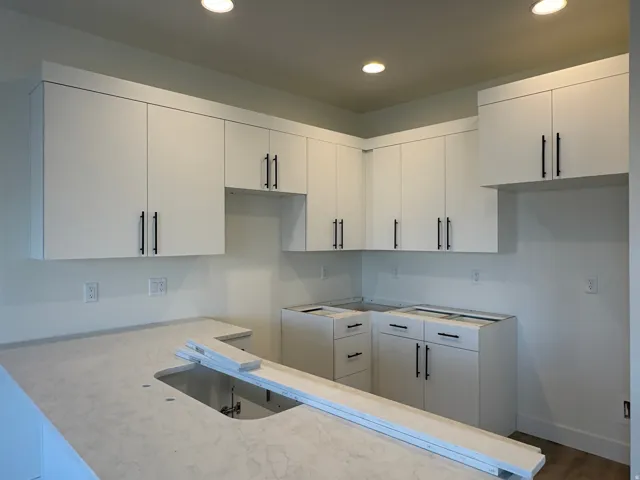 New kitchen featuring white cabinetry with matte black hardware, recessed lighting, and light-toned countertops
