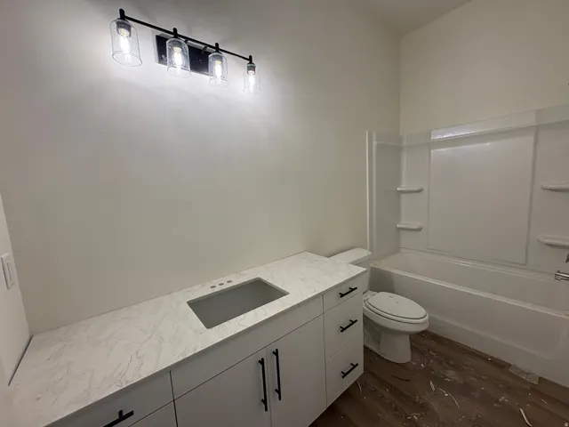 White vanity with integrated sink, stone-finish countertop, and black hardware