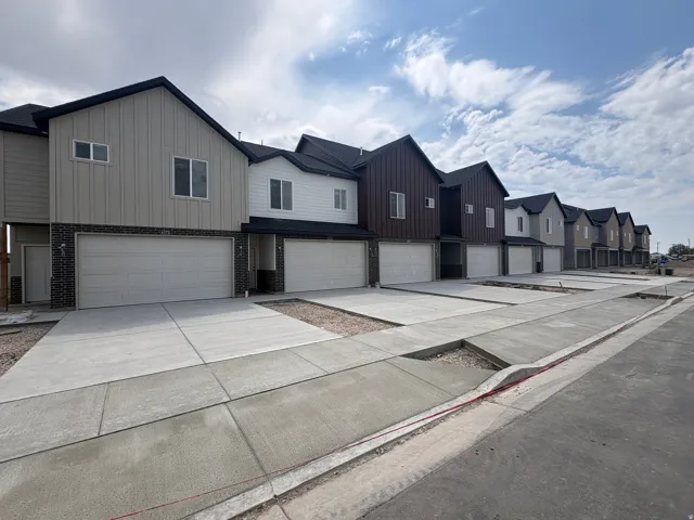 Modern townhome exterior with mixed material siding, attached garage, and concrete driveway