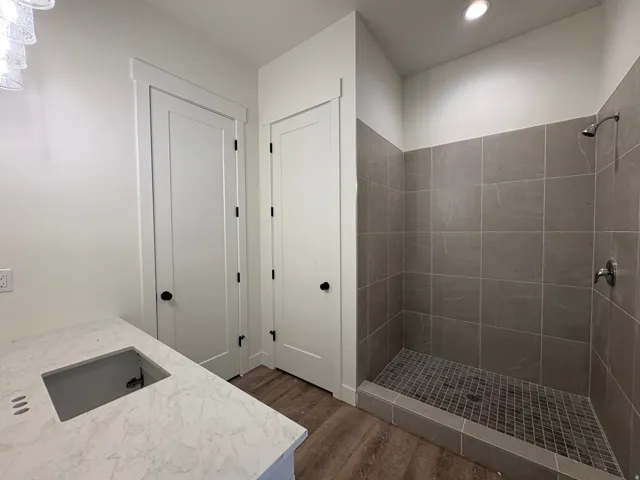 Spacious walk-in shower with gray tile surround and floor, complemented by a white countertop with an integrated sink cutout