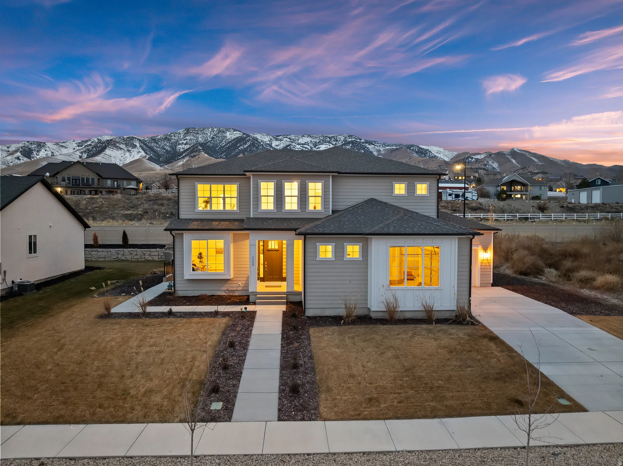 Modern two-story residence with a concrete walkway, attached garage, and mountain backdrop